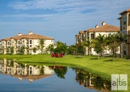 Mature palm trees and a lake with fire pit add visual interest to the flat Florida topography at Altis at Sheridan Village.