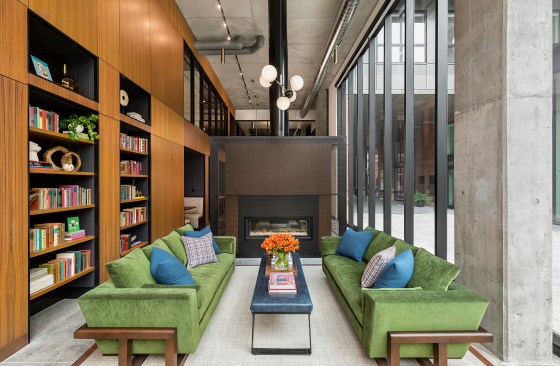 Tall two story lobby of apartment building with living room area and built-in bookcases